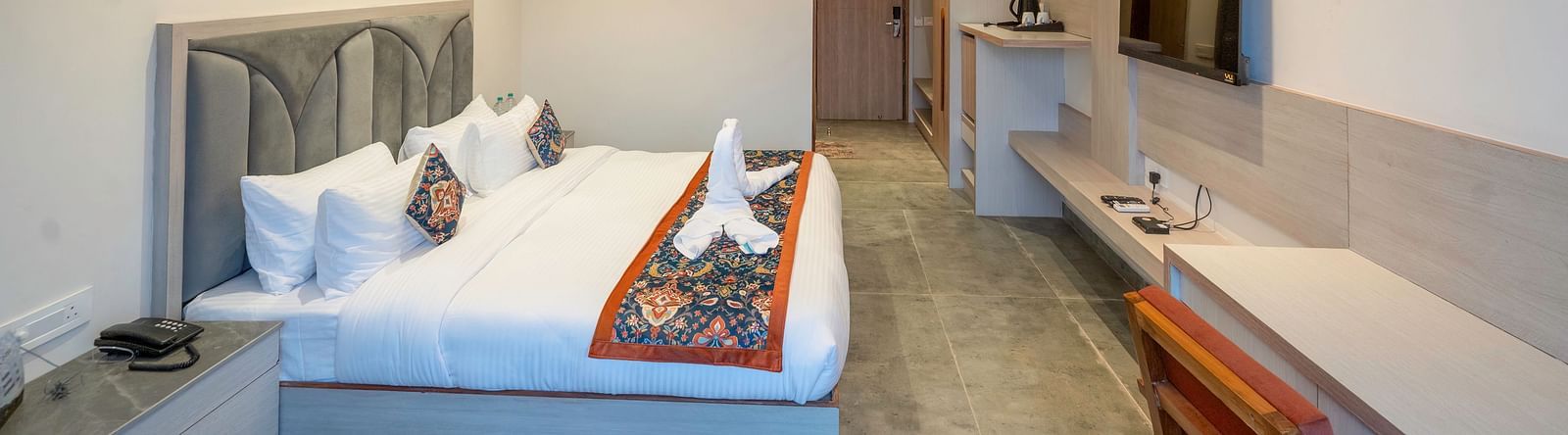 A bright and airy hotel room with a comfortable king-size bed, a flat-screen TV, and a kitchenette, perfect for a relaxing stay.