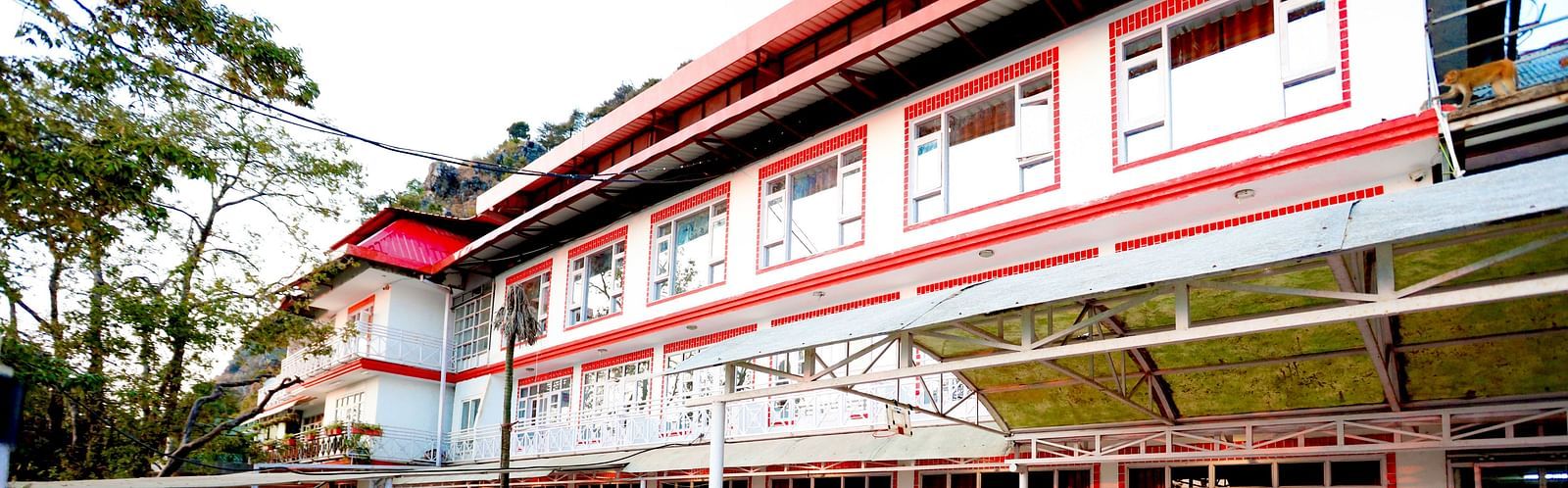 Facade of Amara Hill Queen, Mussoorie with a seating area in front with benches and chairs.