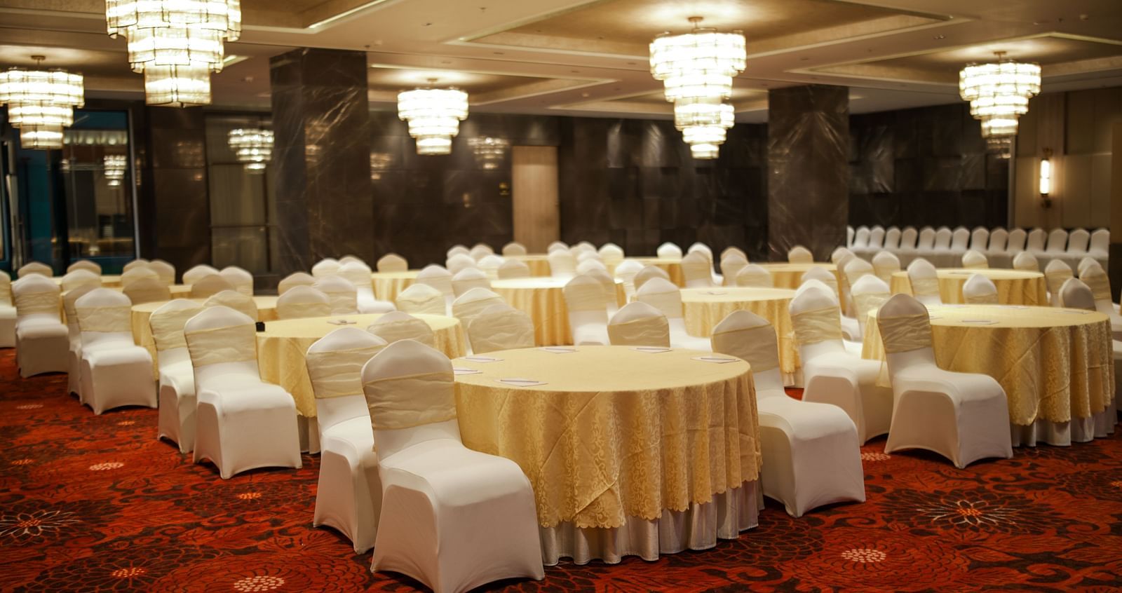 Banquet setup with round tables and white chair covers on a vibrant red carpet at Ramada by Wyndham Sonipat Murthal