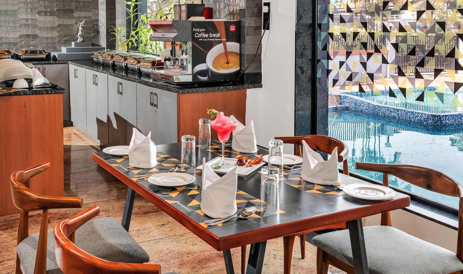 A restaurant dining area with set tables and chairs, overlooking a swimming pool through a glass wall  | The Citi Residenci Hotel Banskopa