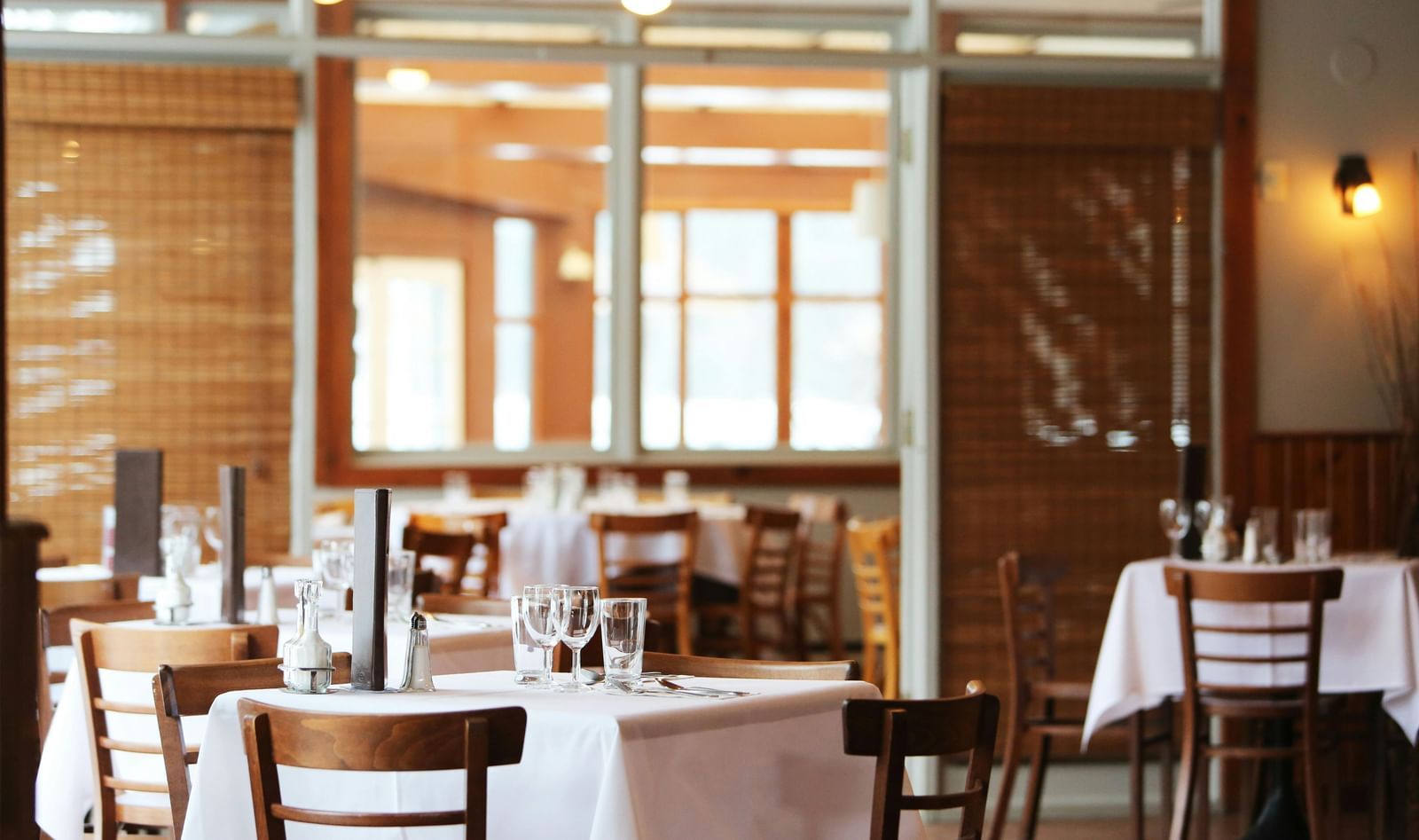 Blurred interior of a restaurant with set tables and chairs, suggesting a quiet or unoccupied setting.