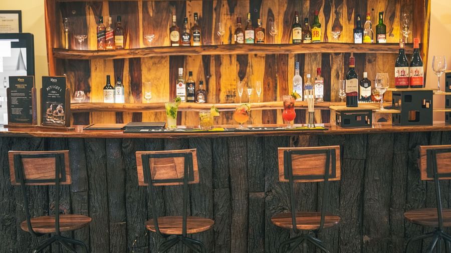 Bar counter with various alcohol bottles displayed and chairs placed in front of the counter