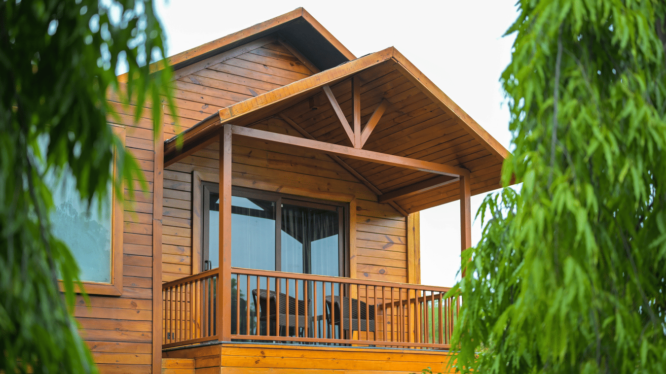 Wooden cottage exterior with a balcony surrounded by trees at The Ananta Udaipur.