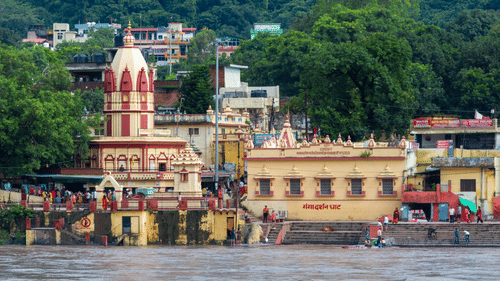 An image of Ganga river surrounded and near to it there are temples, trees, and residential areas 