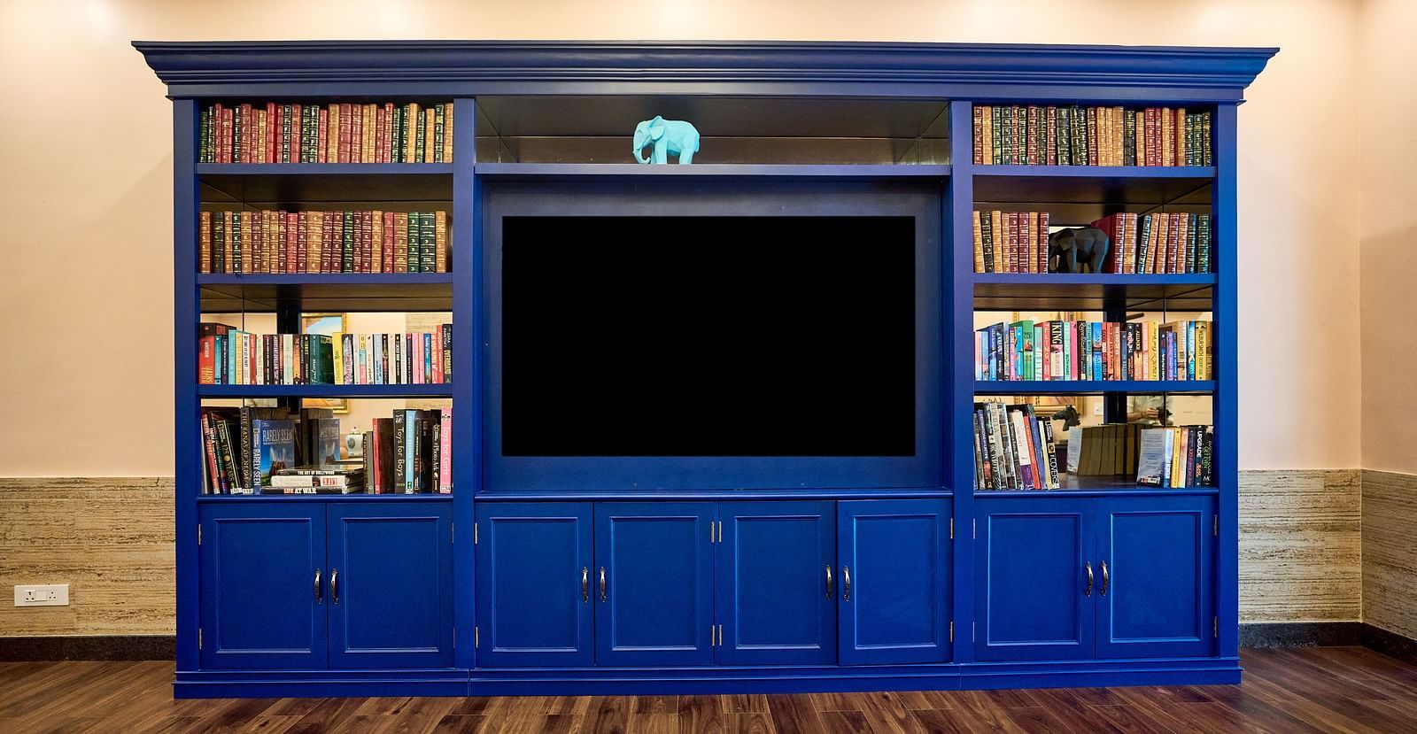 A large cupboard with books neatly arranged for display at Mayfair Manor, Alibag