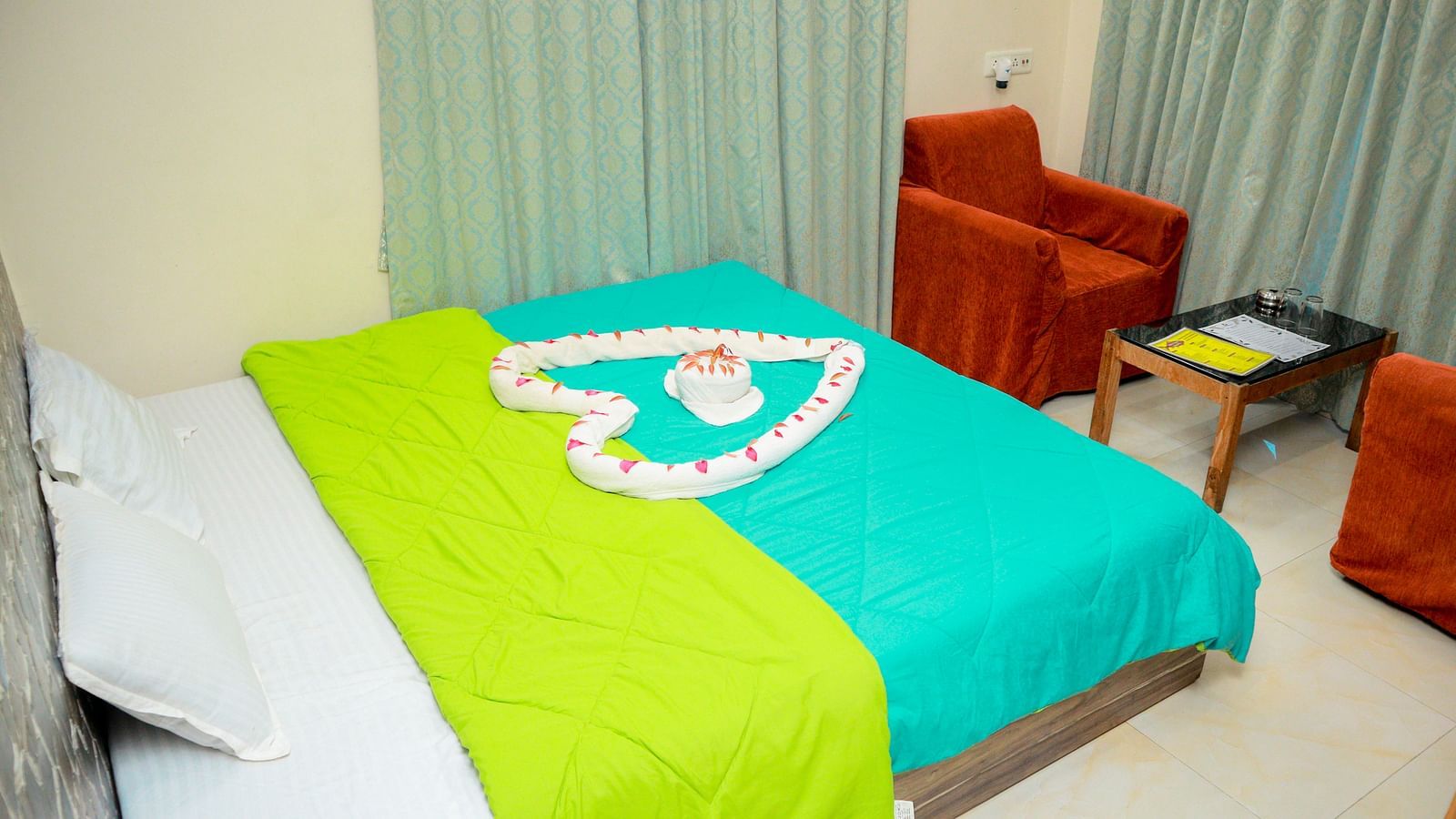 image of a king size bed with a heart shaped decoration over it with flower petals and a family seating area in the corner