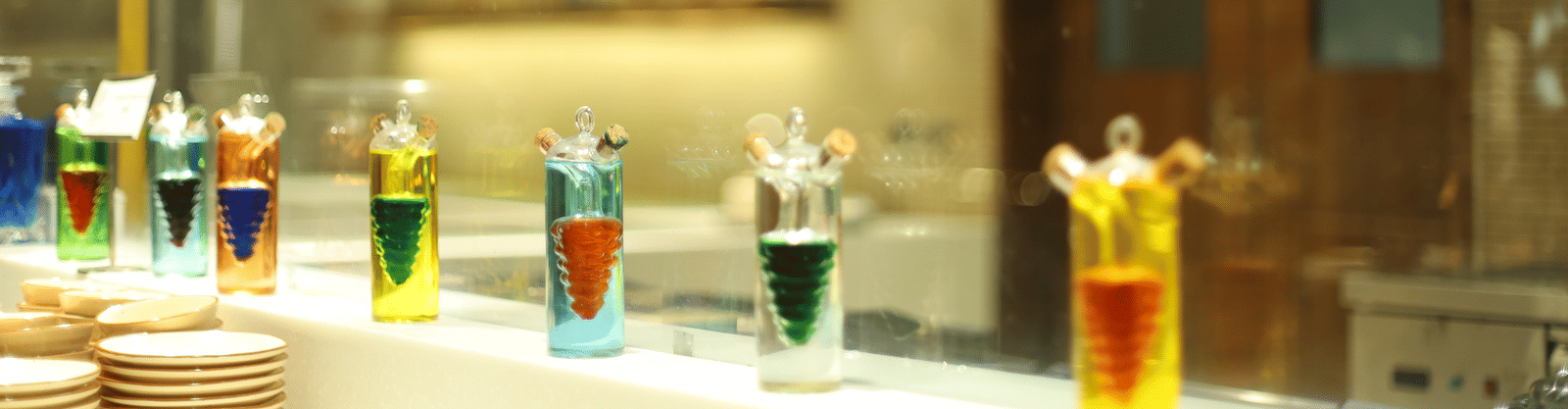 A vibrant display of colourful liquid art or cocktail ingredients behind glass at a bar in Pushkara Resort & Spa.