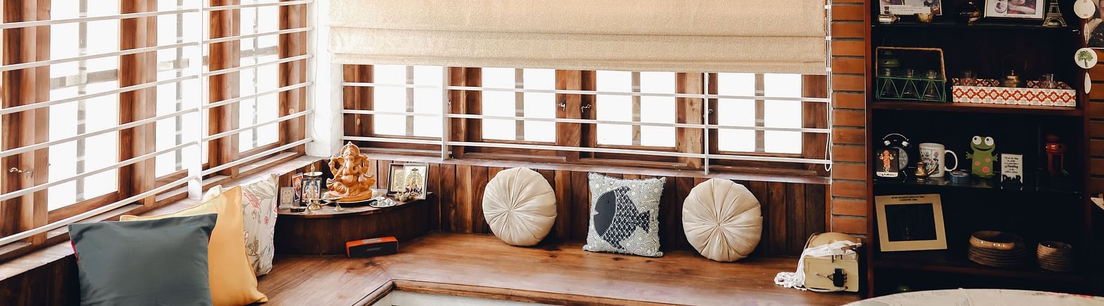 a large l-shaped sofa and a shelf with things kept in the Living Room at Ananda Holiday Home, Wayanad