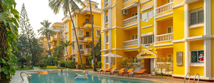 An image of an outdoor swimming pool framed by yellow buildings.