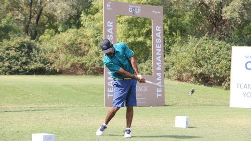 Golfer preparing to tee off at a scenic corporate golf event with visible brand signage.