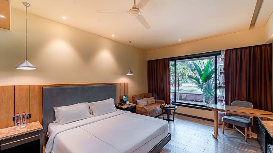 Club Room features a spacious bed, cushioned sofa, and a large window showcasing a natural view at Crescent Spa & Resort, Indore