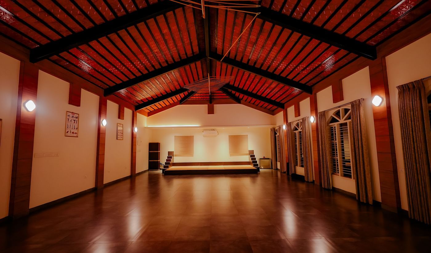 An empty event space or hall with a high ceiling and wooden floor at Nirantara Resort & Spa.