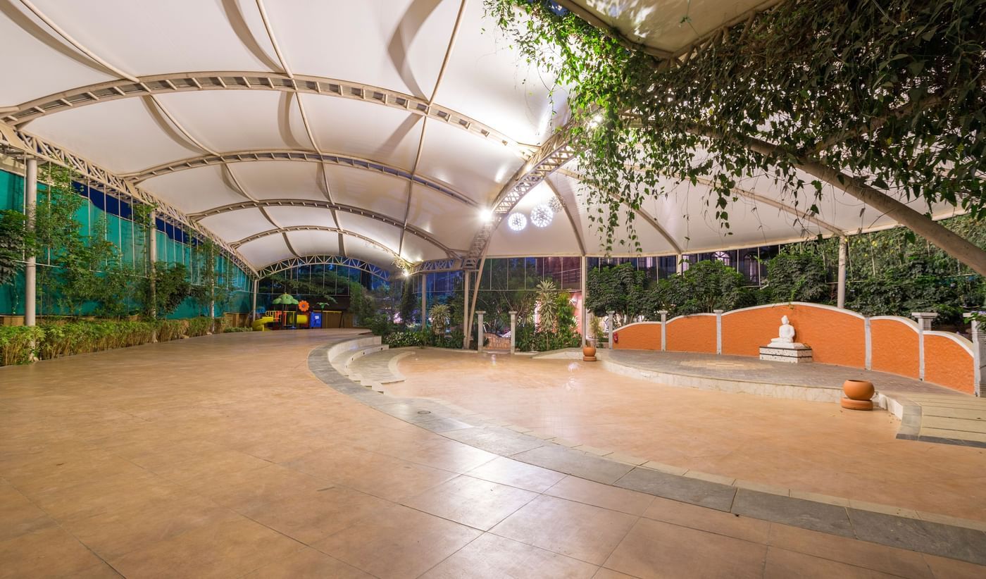 Spacious outdoor covered walkway at Nirantara Resort with greenery and seating.
