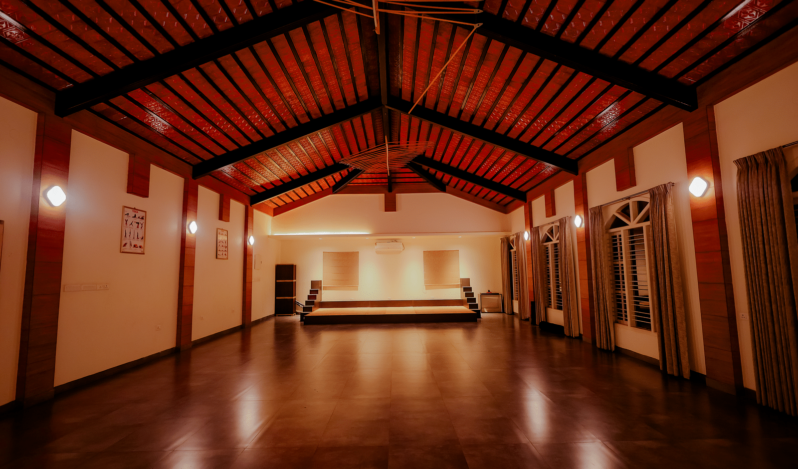 An empty event space or hall with a high ceiling and wooden floor at Nirantara Resort & Spa.