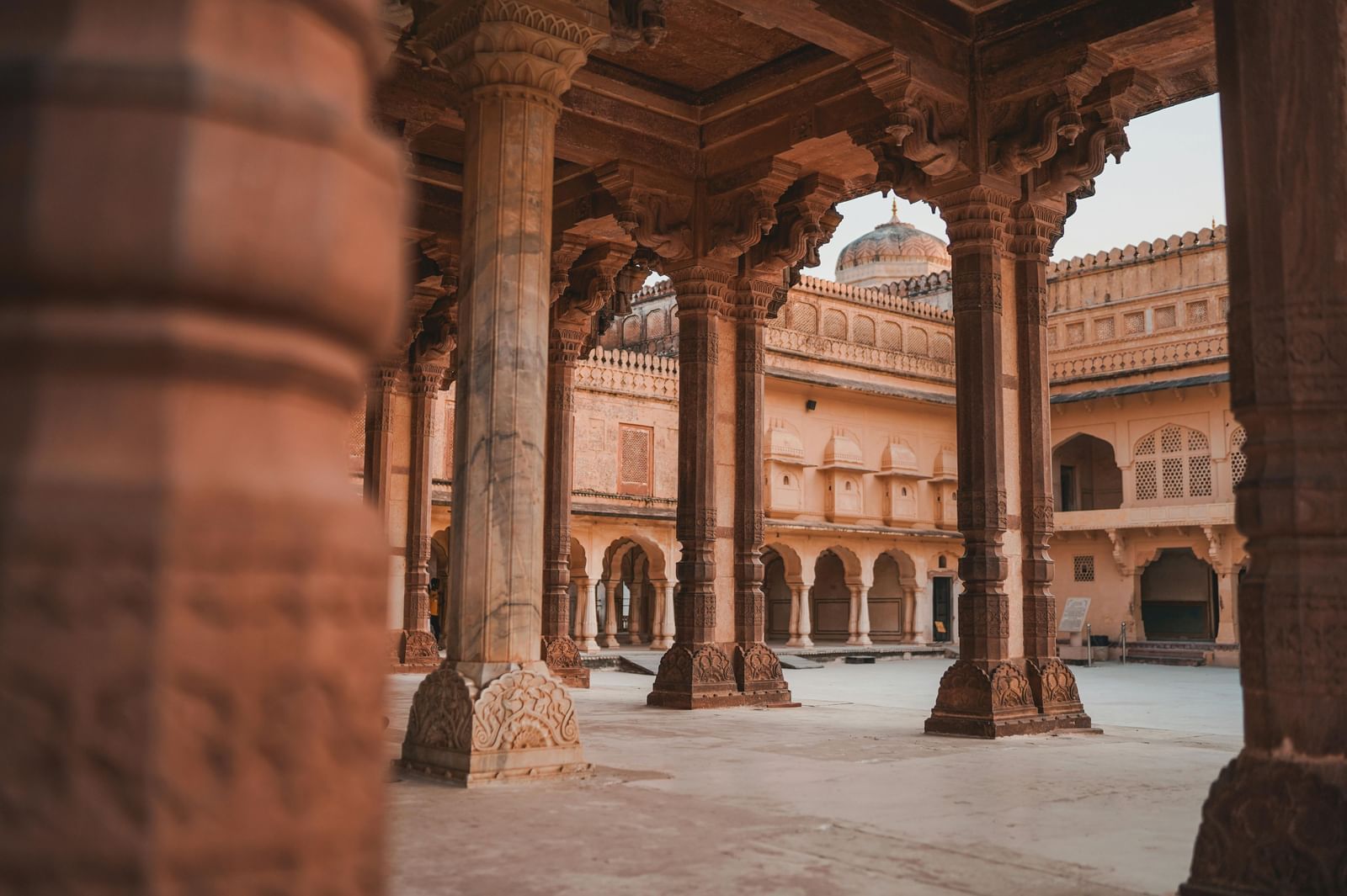Ornate stone archways and columns frame a traditional Indian courtyard, hinting at historical architecture.