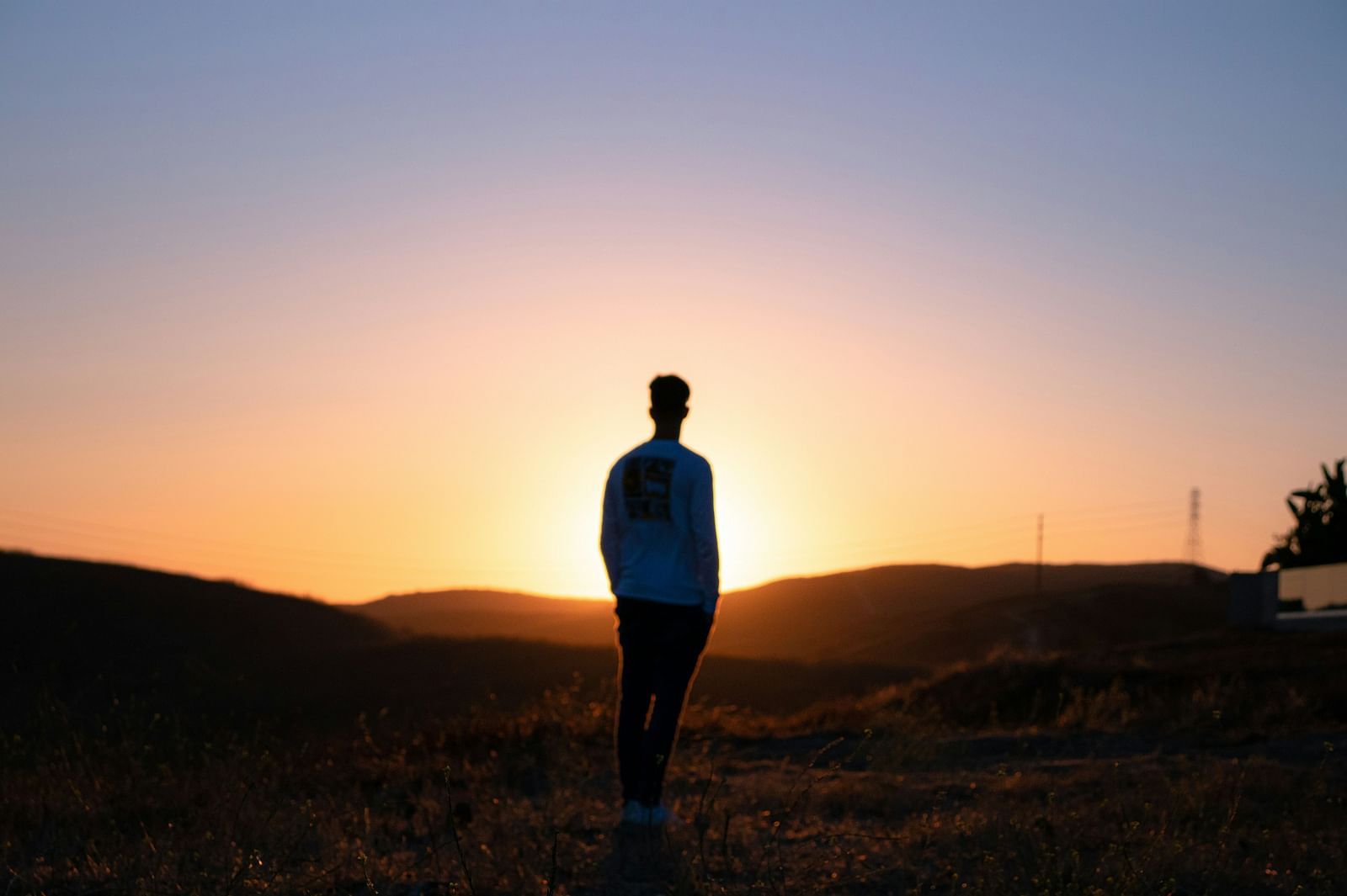 A silhouette of a person standing against a sunset. 