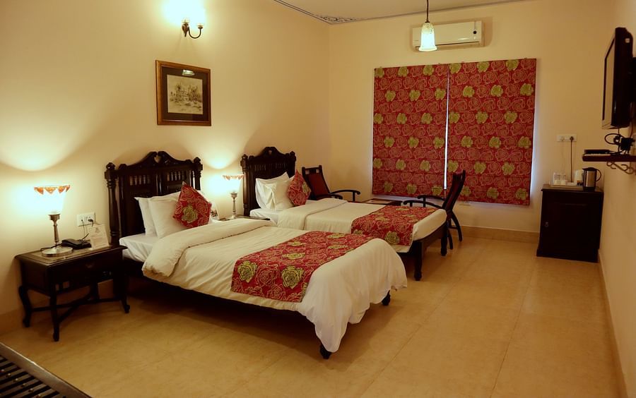 Twin beds with beautiful red bedsheets and red pillow covers at Junior Suite at Suryaa Villa Jaipur