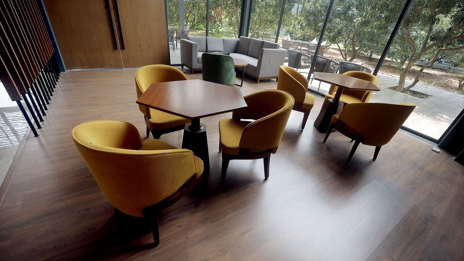 Elegant group seating with round wooden tables and plush yellow chairs in a sunlit room at Wyndham Garden.
