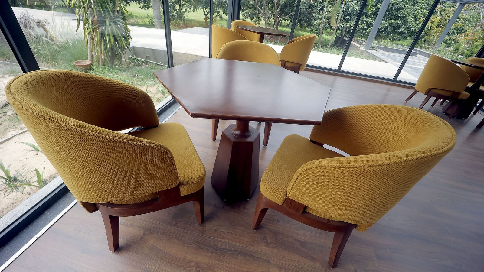 Cosy wooden table setting with mustard yellow armchairs beside large windows at Wyndham Garden.