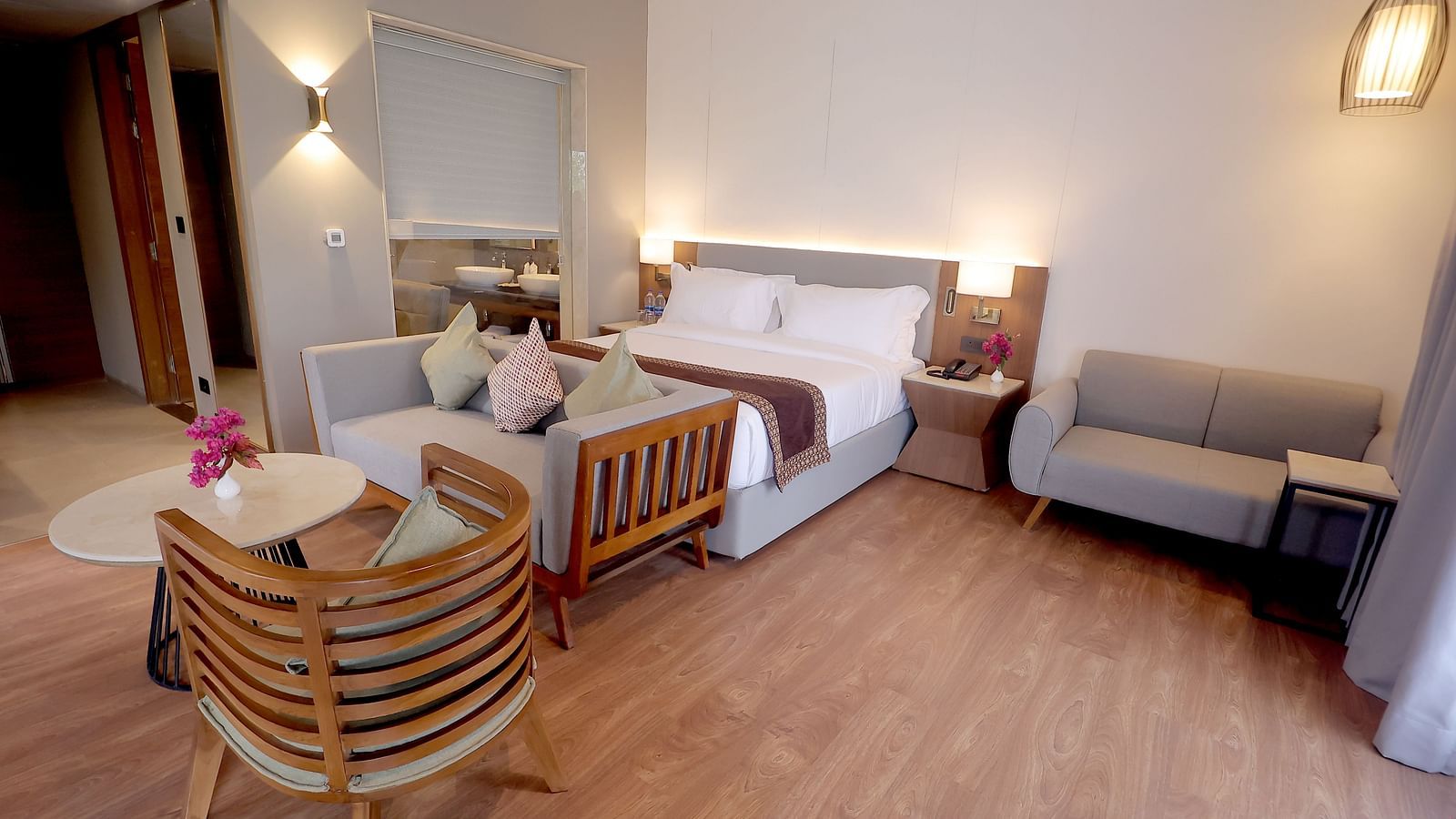 Elegant room with a king size bed, grey settee, two stylish chairs, and wooden flooring at Wyndham Garden.