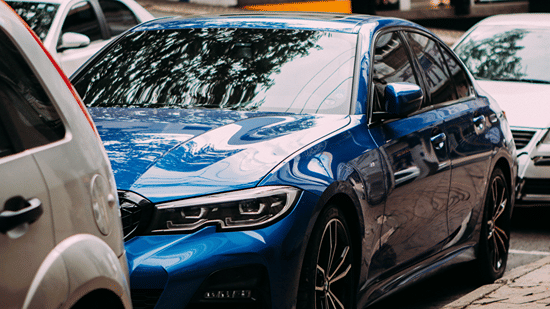 Modern blue sedan car parked in an outdoor lot, representing car rental and valet parking services.