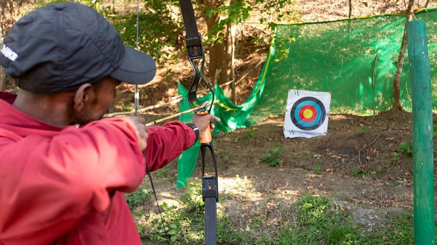 Man aiming at a target in an outdoor shooting range activity. | Stone Wood Jungle Resort, Dandeli