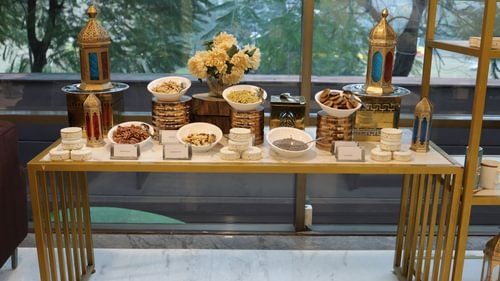 Buffet table with labeled bowls of food, a floral centerpiece, and ornate lanterns. - Heritage Village Resorts & Spa