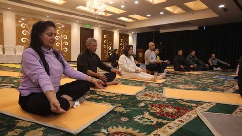 An image of group of people meditating on a yoga mat in a room at Heritage Village Resorts & Spa