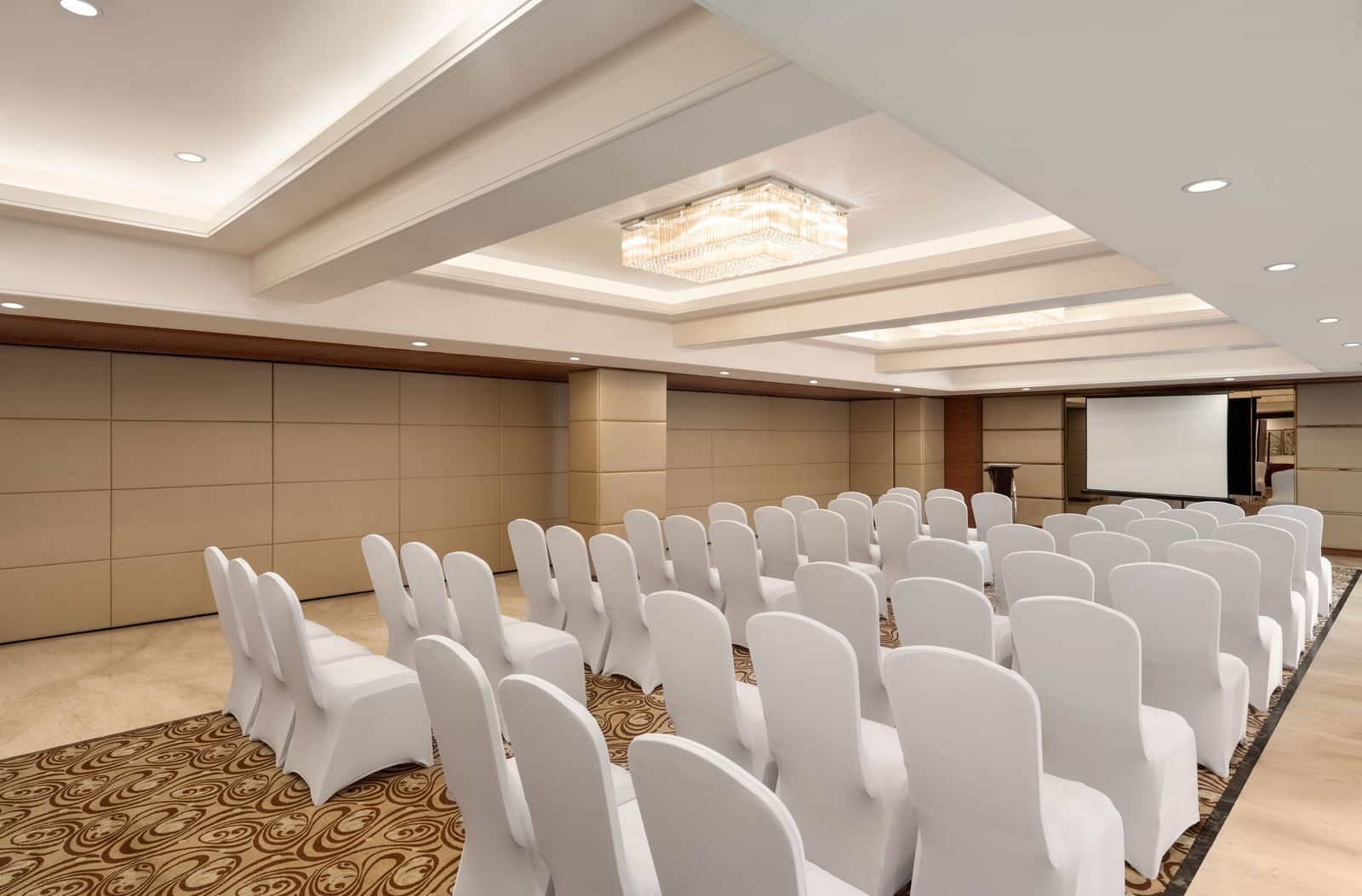 Conference hall with white chairs in theater-style arrangement at Ramada by Wyndham Ghaziabad Vasundhara