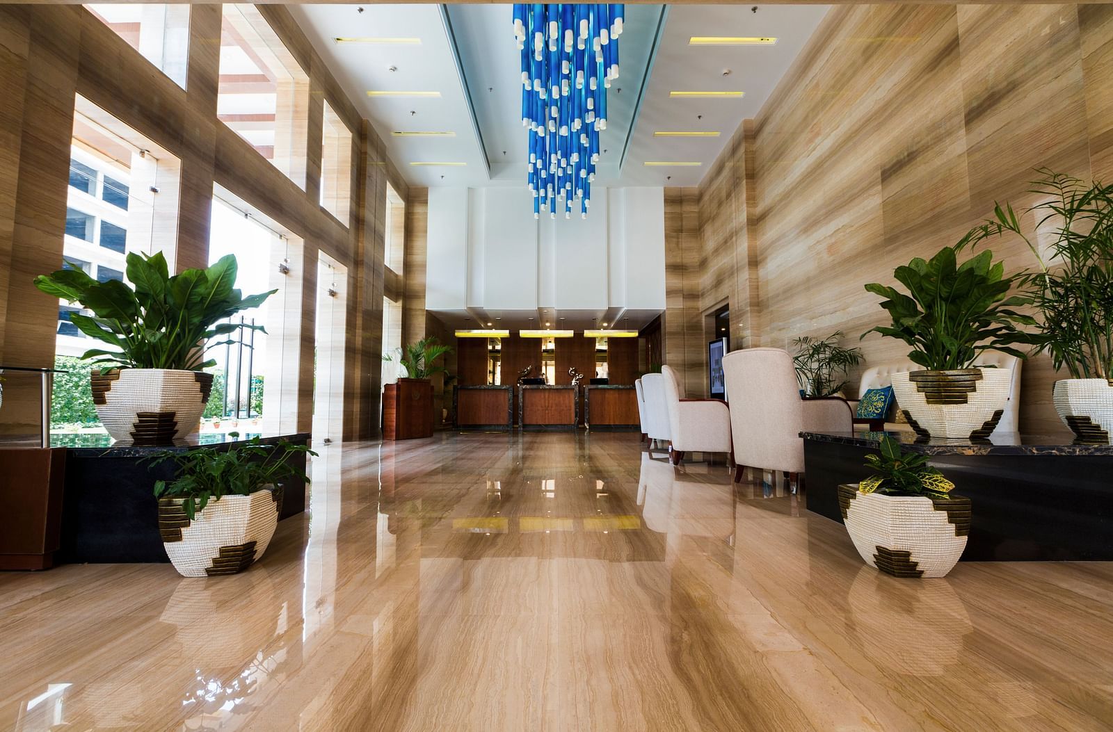 An expansive lobby with ample of natural light coming from outside of the hotel featuring a reception desk at the far end of the lobby - Ramada by Wyndham, Ghaziabad, Vasundhara