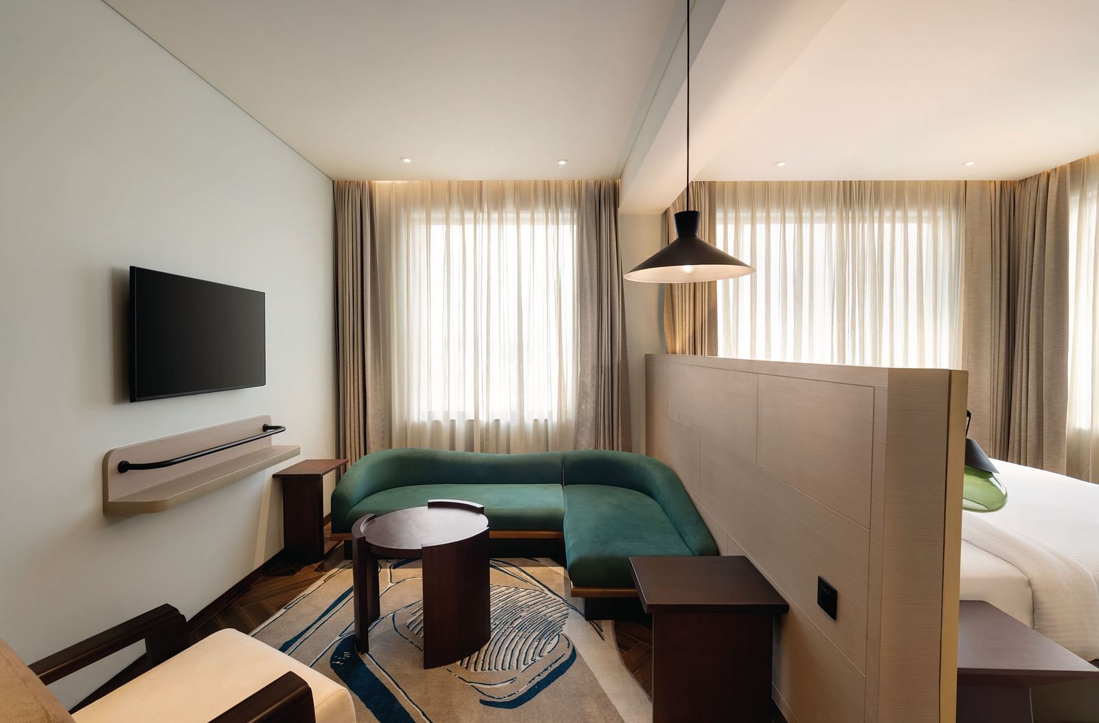 Ramada Encore by Wyndham, Bhiwadi | Hotel room with green couch, bed, TV, and decorative lighting.
