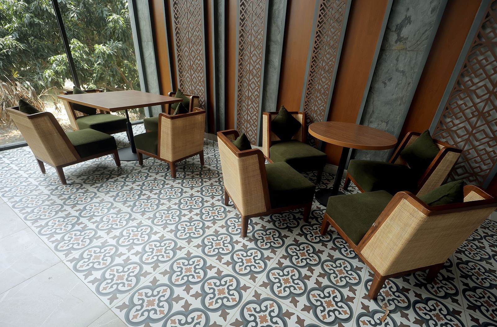 Sophisticated indoor dining with patterned flooring and upholstered wooden armchairs beside tall windows at Wyndham Garden.