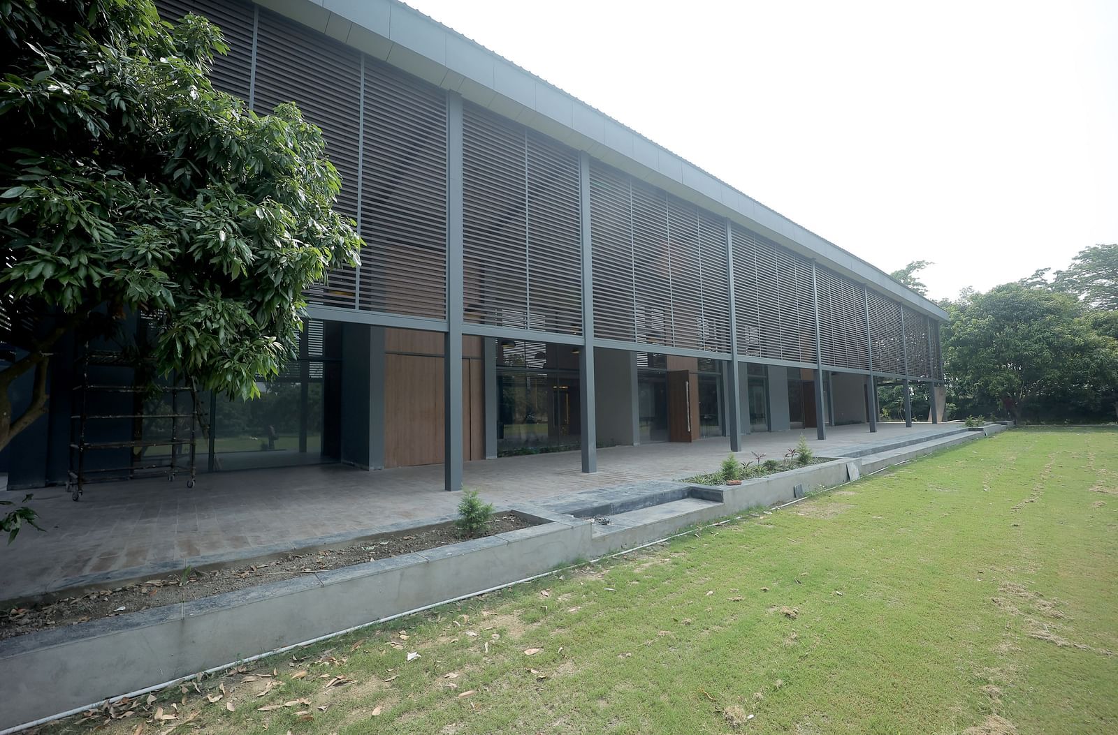 Modern building façade with large glass windows facing a well-kept lawn and trees at Wyndham Garden.