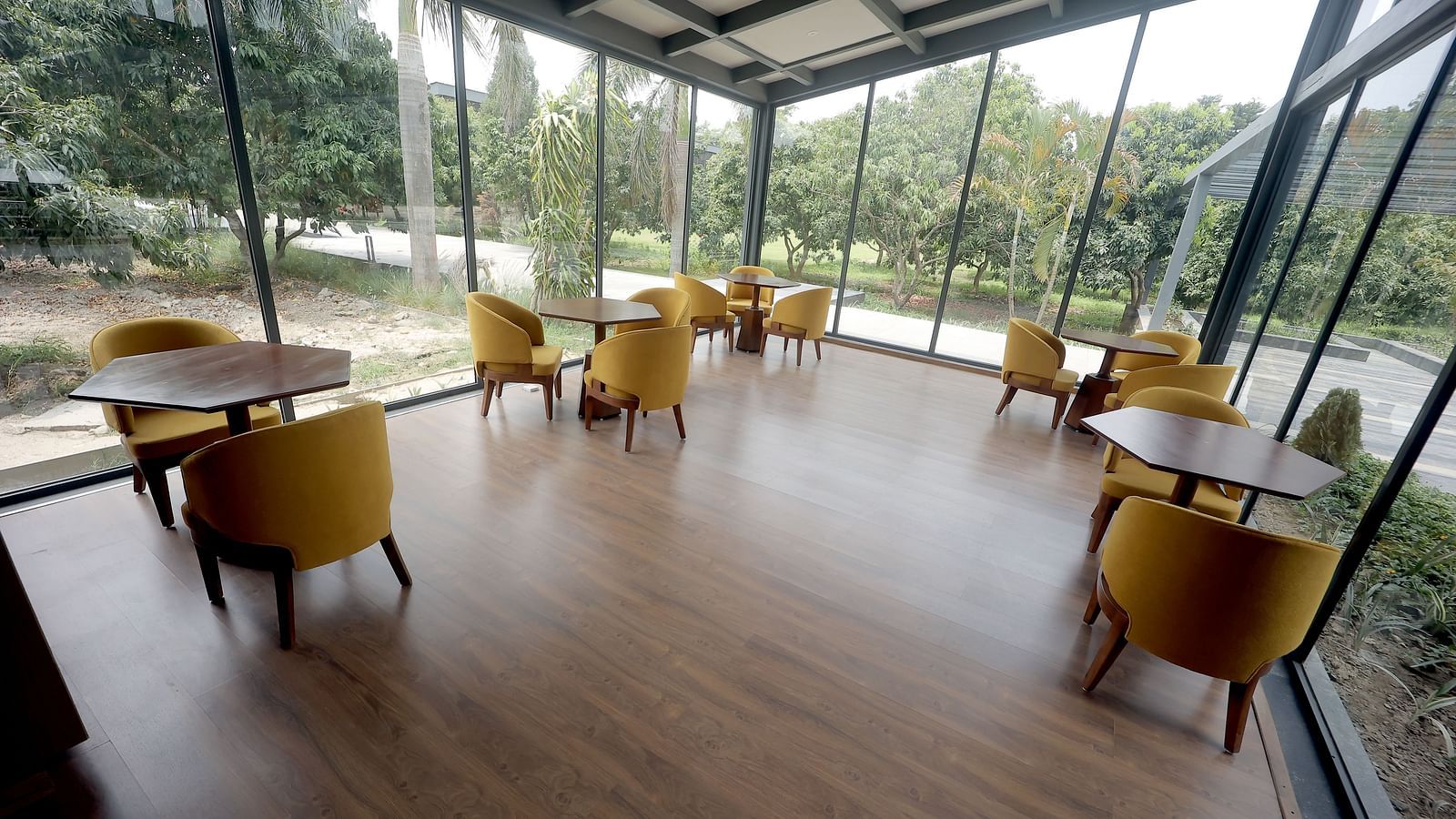 Bright dining area with floor-to-ceiling windows and yellow chairs overlooking lush greenery at Wyndham Garden.