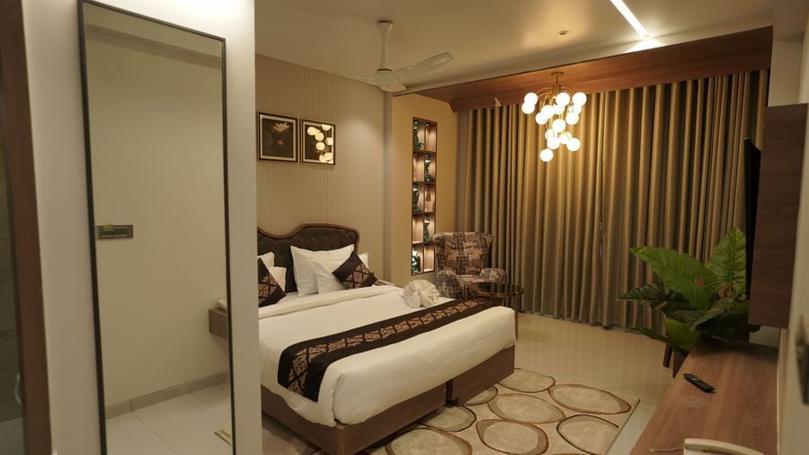 Suite Room at Pride Comfort, Dwarka with a double bed, a television and a chandelier.