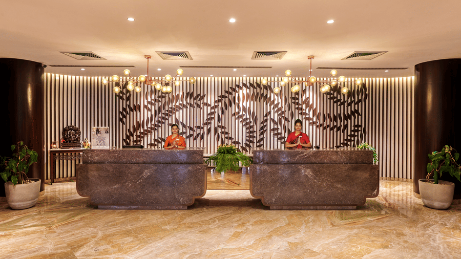 Two receptionists at the lobby of Pride Premier Nagpur desk doing namaste which is a way to greet guests.