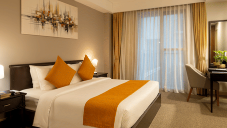 One Bedroom Suite bedroom at Central Mansions, Phnom Penh with a king bed, work desk, and large windows.