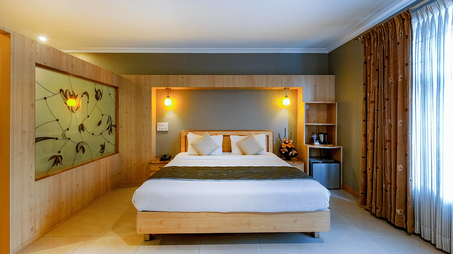 An elegant Suite with a stylish headboard and large bed - Cross Roads Inn, Bengaluru