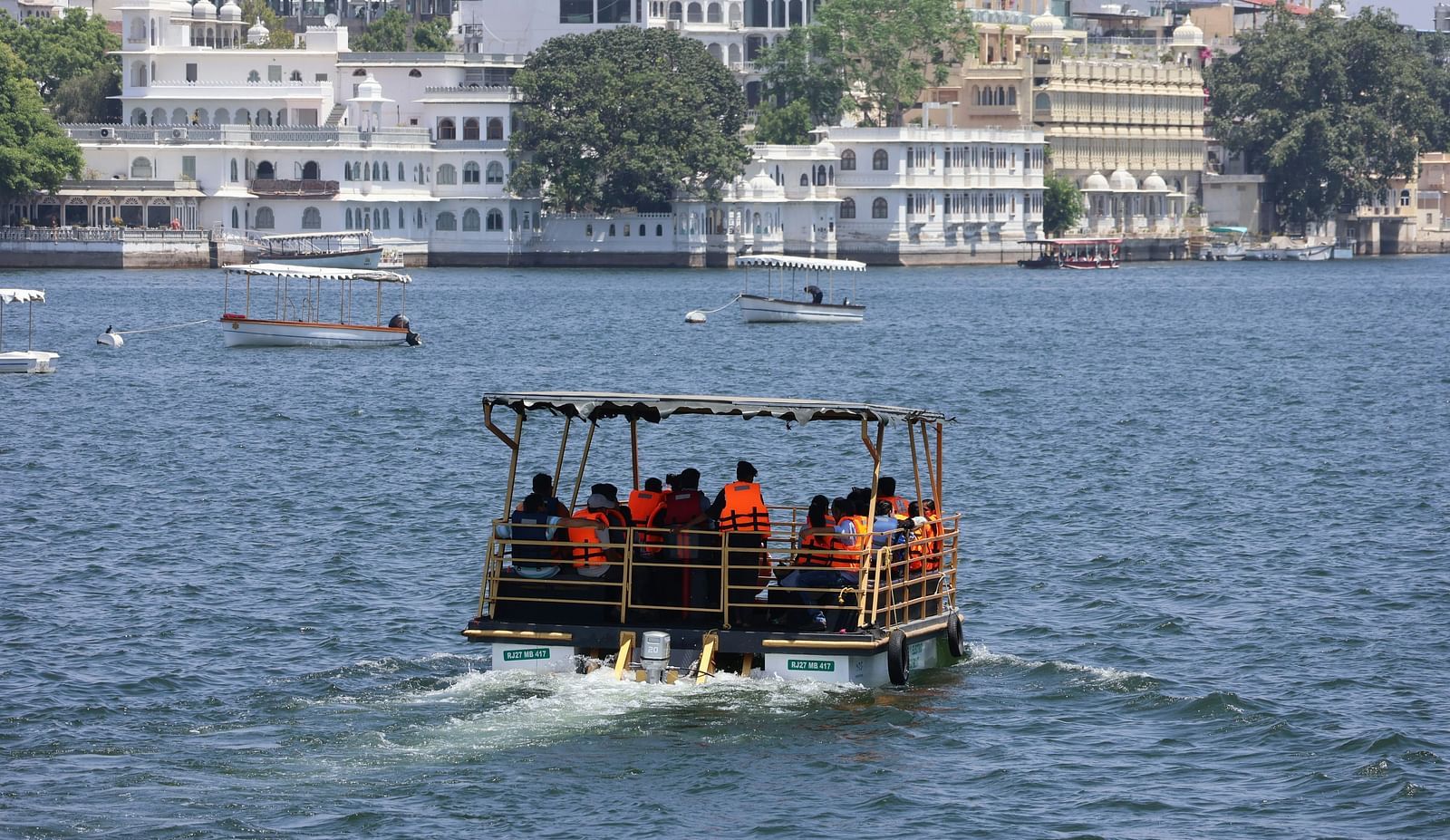 A boat travelling in Lake Pichola towards the city palace - City Palace Udaipur near Hotel