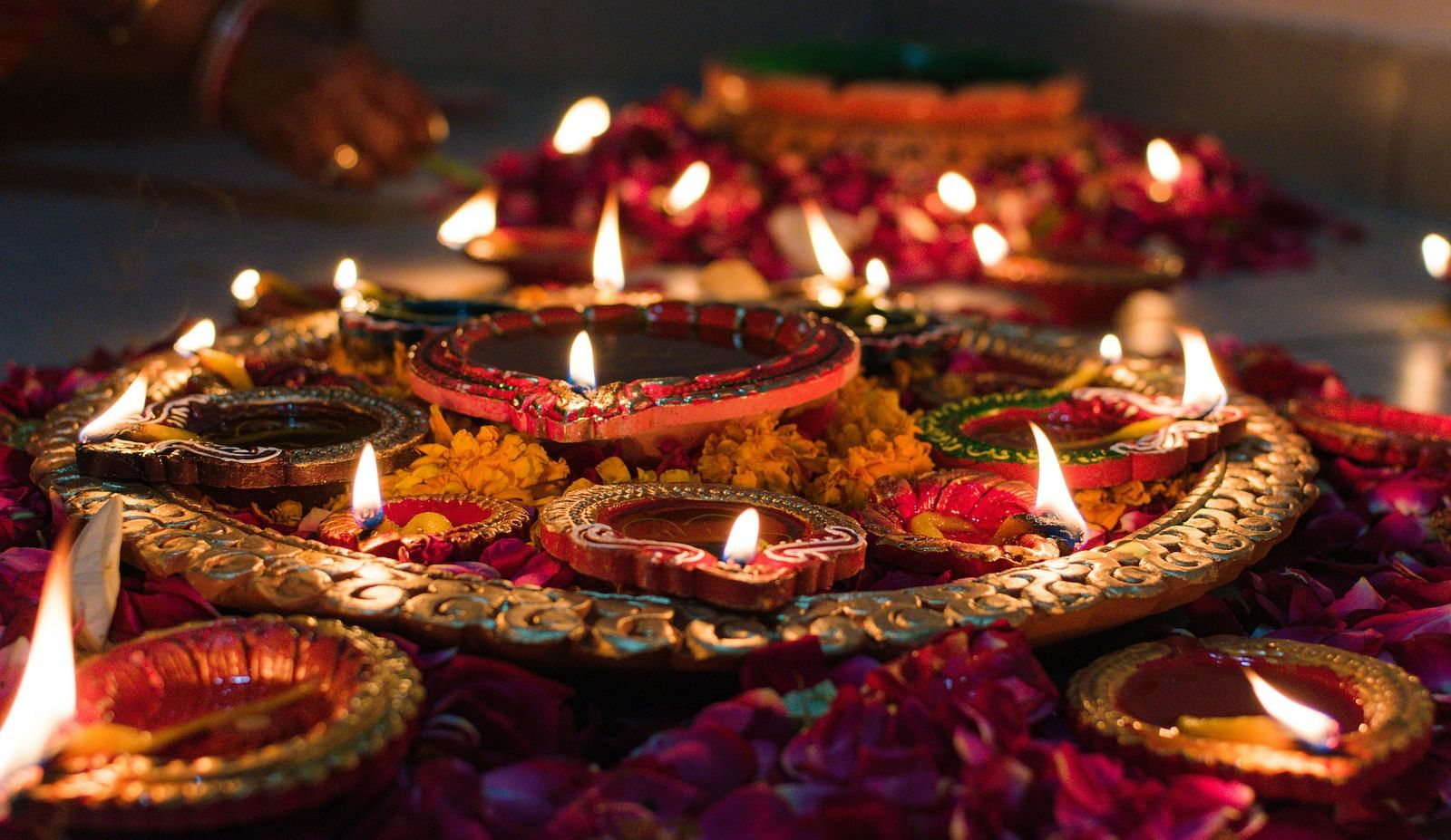A close up shot of a copper plate with many lit diyas kept on it