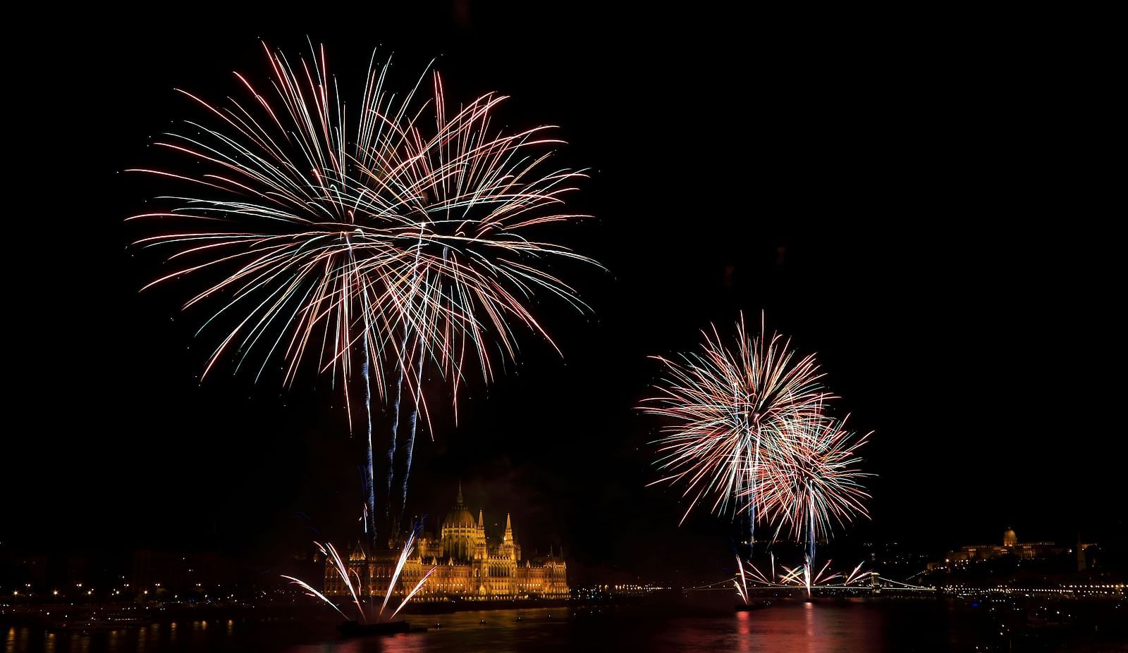 An overview of fireworks in the sky with the light illuminating on the waterbody below
