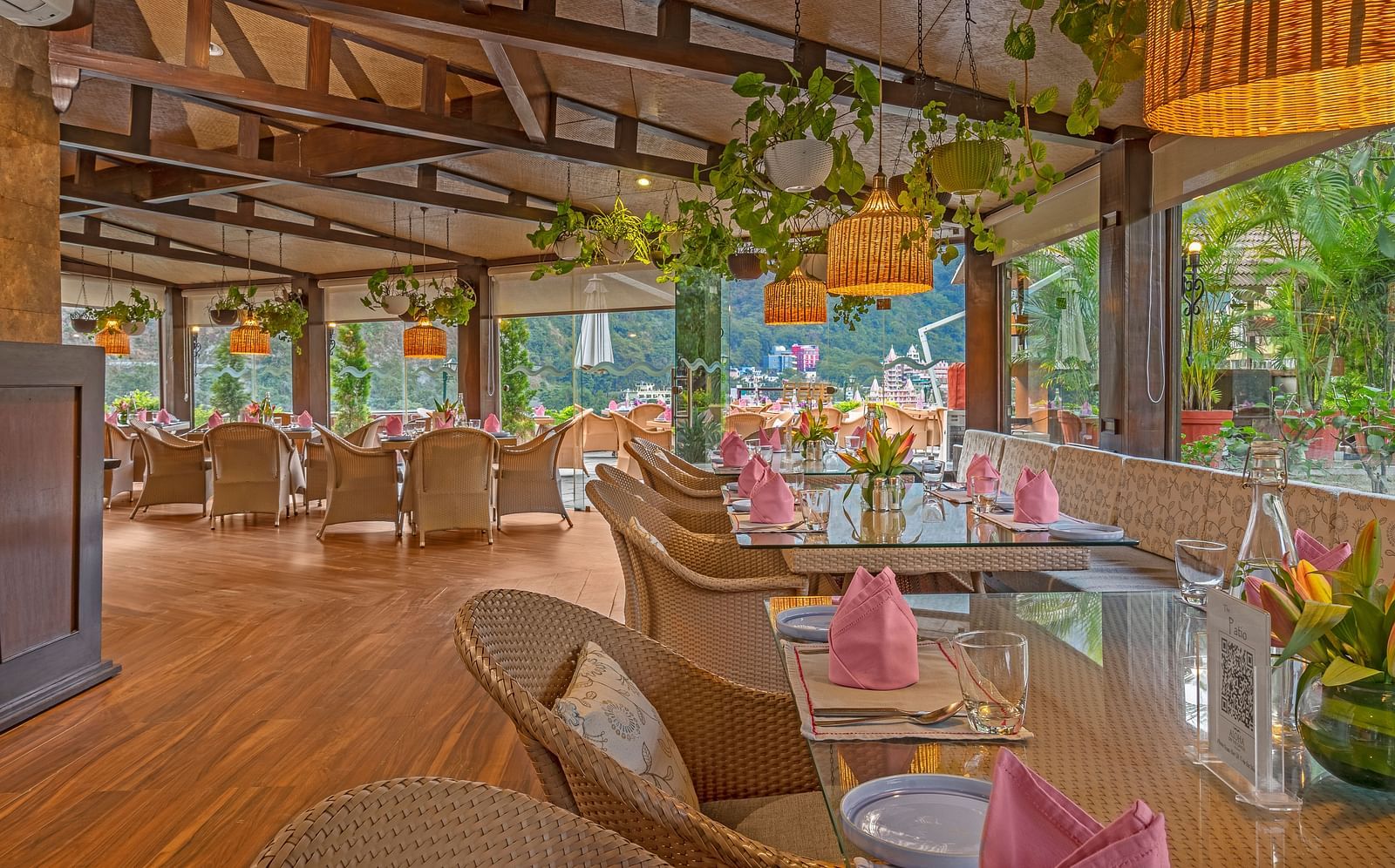 A spacious restaurant with a wooden floor and exposed wooden beams on the ceiling. Large windows offer views of the outdoors.
