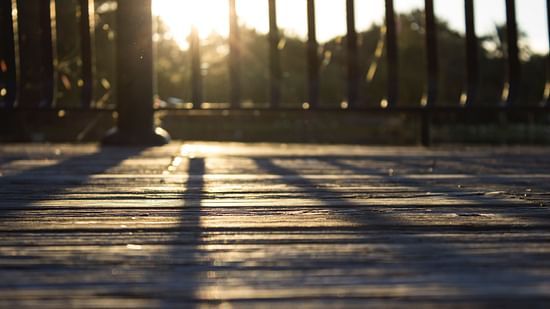 a wooden desk with sun shining and the railings with sun in the background