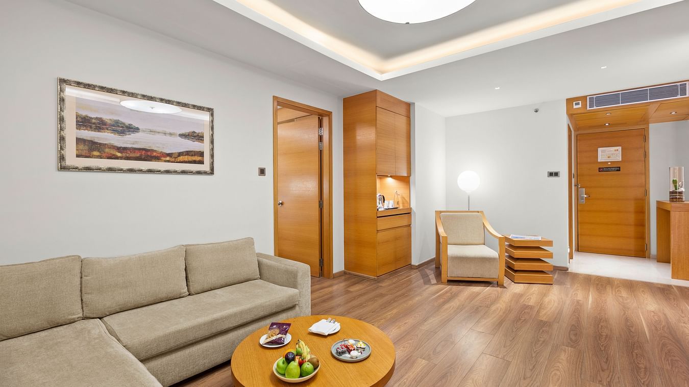 Living room with a cozy sofa in the corner, round table, and hanging ceiling light at The Residency Towers Coimbatore