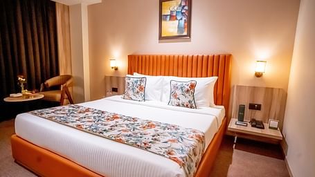 Superior Room at ASTER GRAND BY ZENQ SAKET with a bed, bed side table, a chair and a window with curtain in the background.
