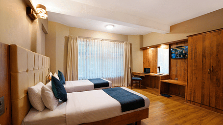 An elegant room featuring twin beds and wooden furnishings - Cross Roads Inn, Bengaluru