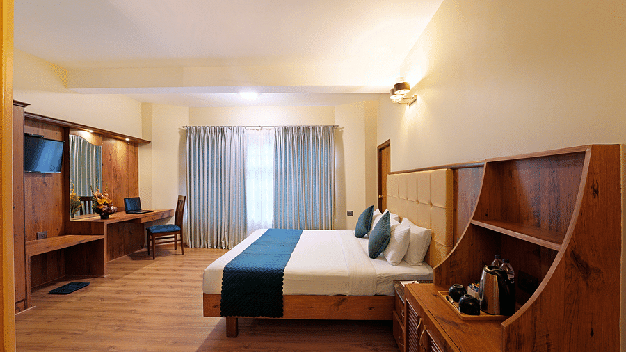 An Executive Room featuring a queen size bed, wooden decor and large windows - Cross Roads Inn, Bengaluru