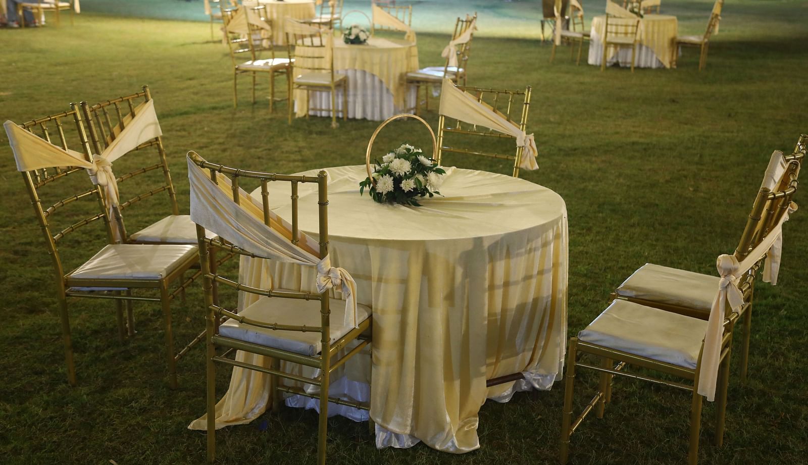 Round table setup with chairs in an open lawn event area at Tisya Farms, Gurgaon.