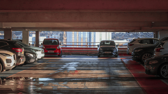 Covered parking area with multiple cars parked in designated spaces inside a multi-level parking garage.