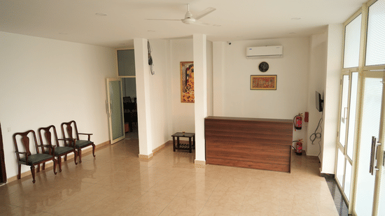 Spacious hotel lobby with a reception desk, seating area and large windows.